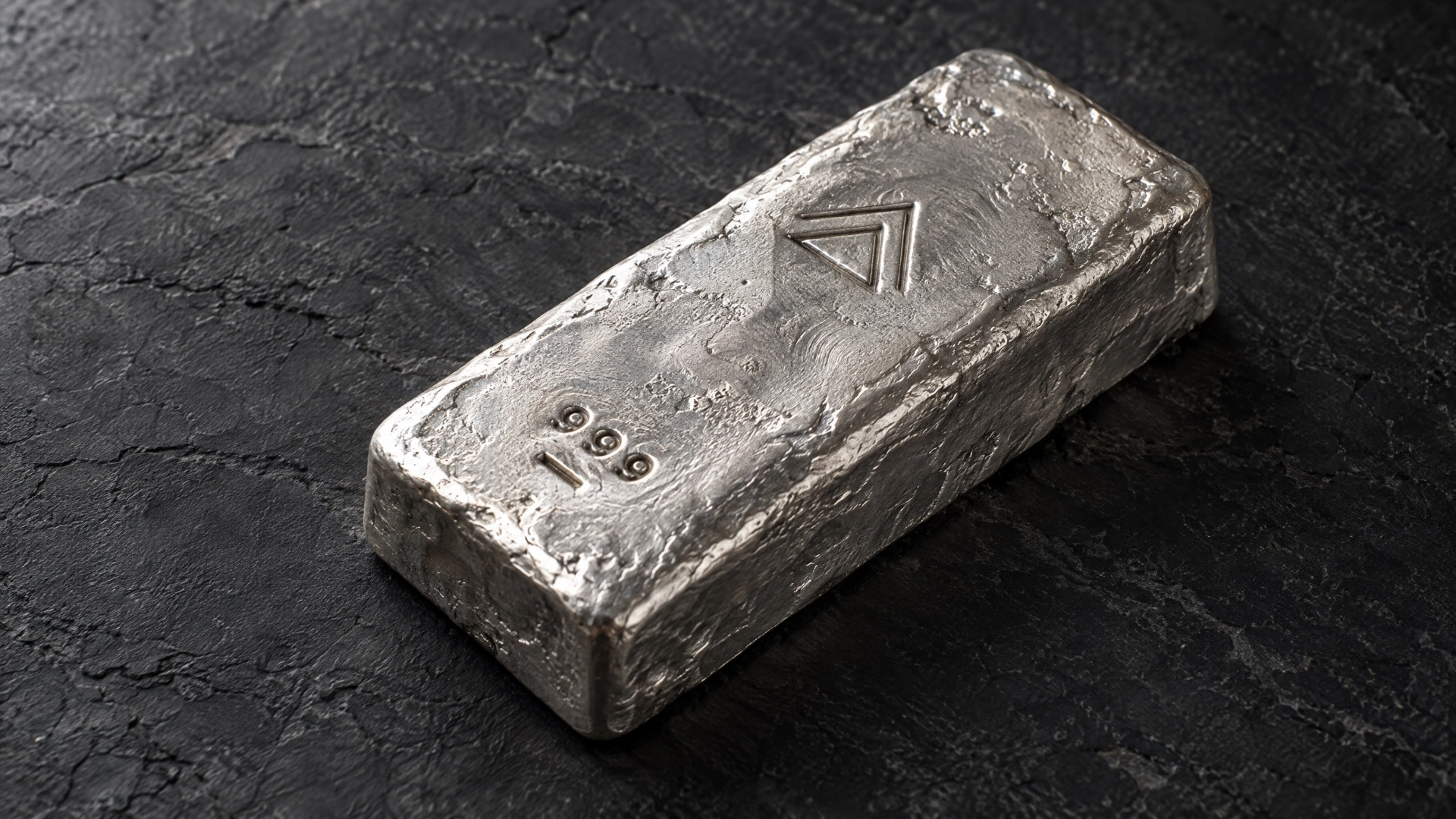 Close-up of a rough hand-poured silver bar showing an abstract maker's mark and cast surface texture